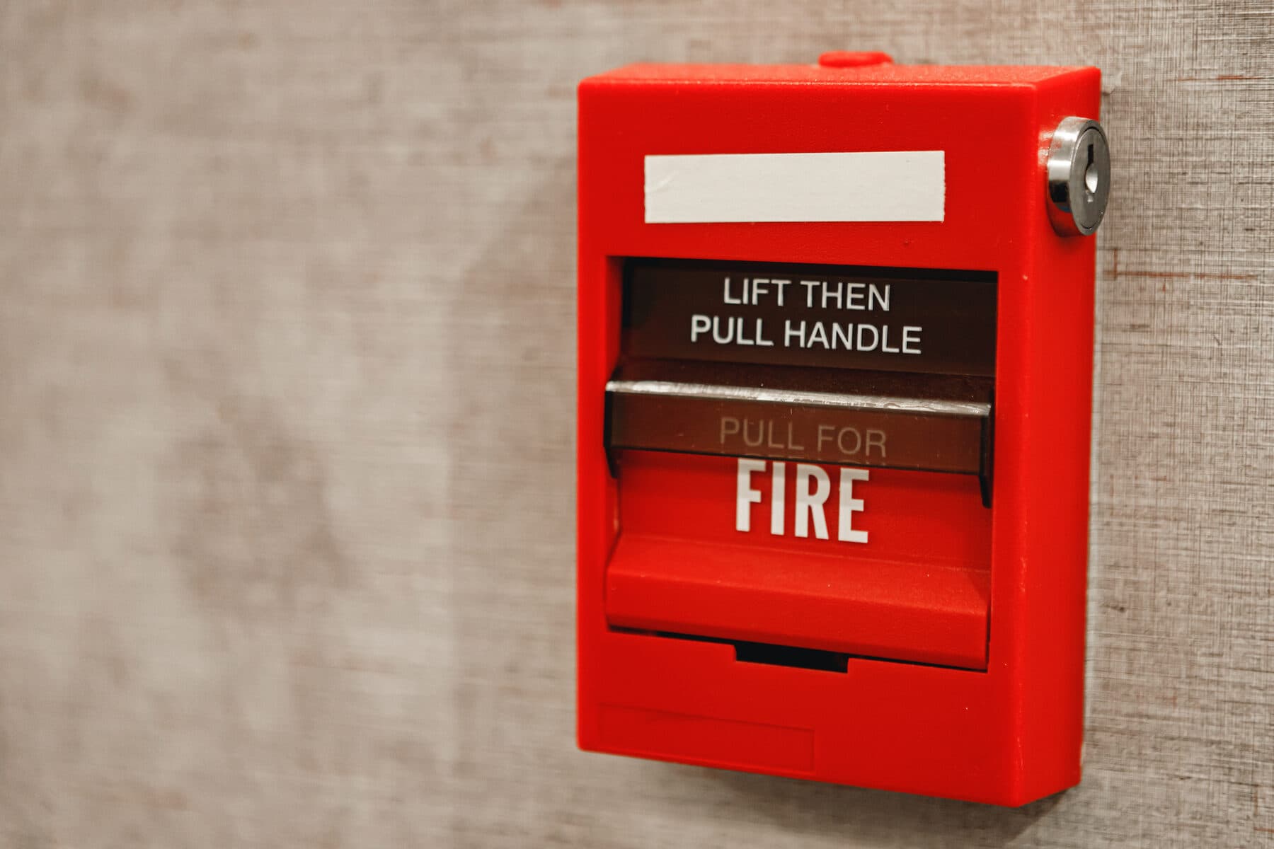 Red manual fire alarm pull station mounted on a wall