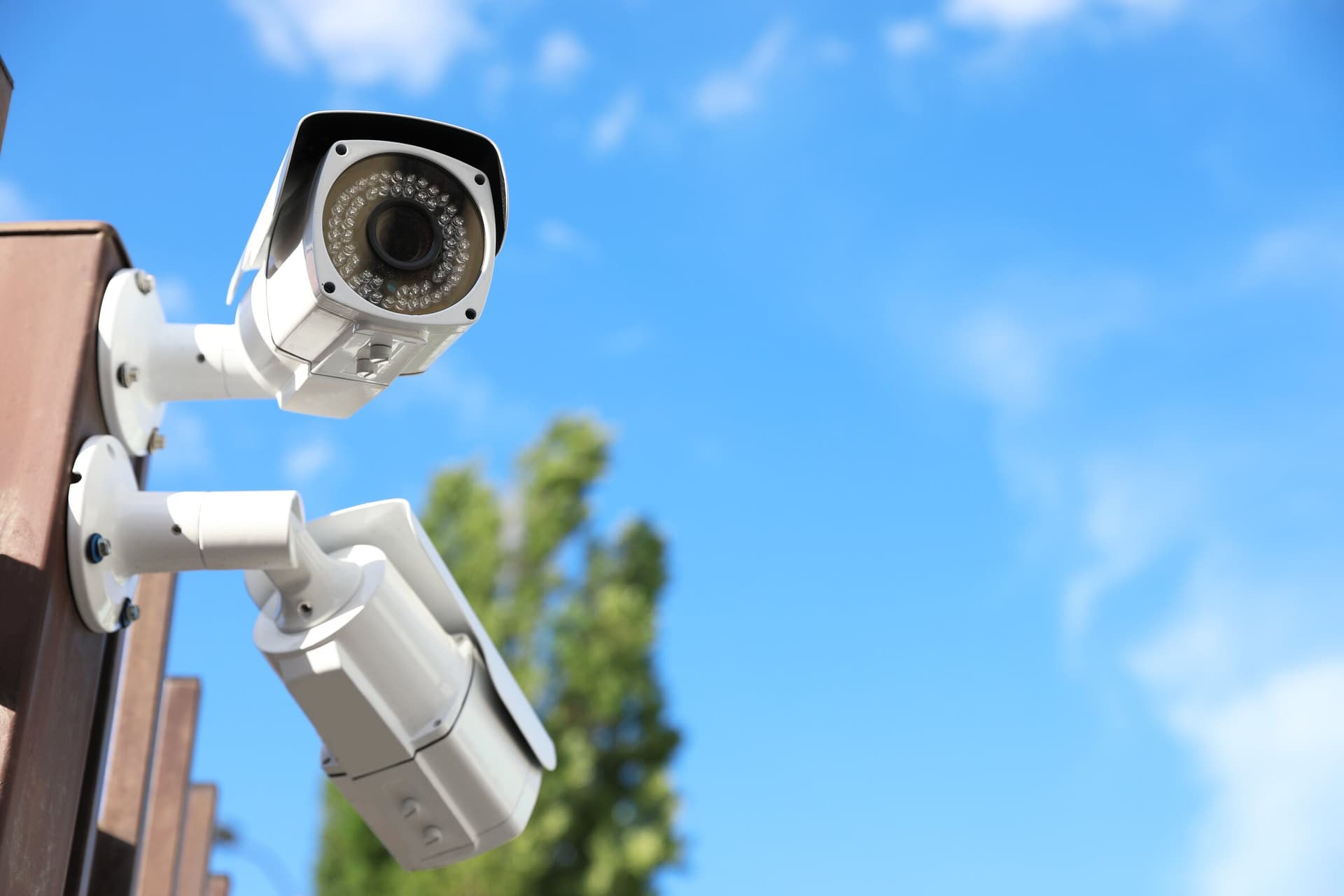 Outdoor security cameras mounted against a bright blue sky